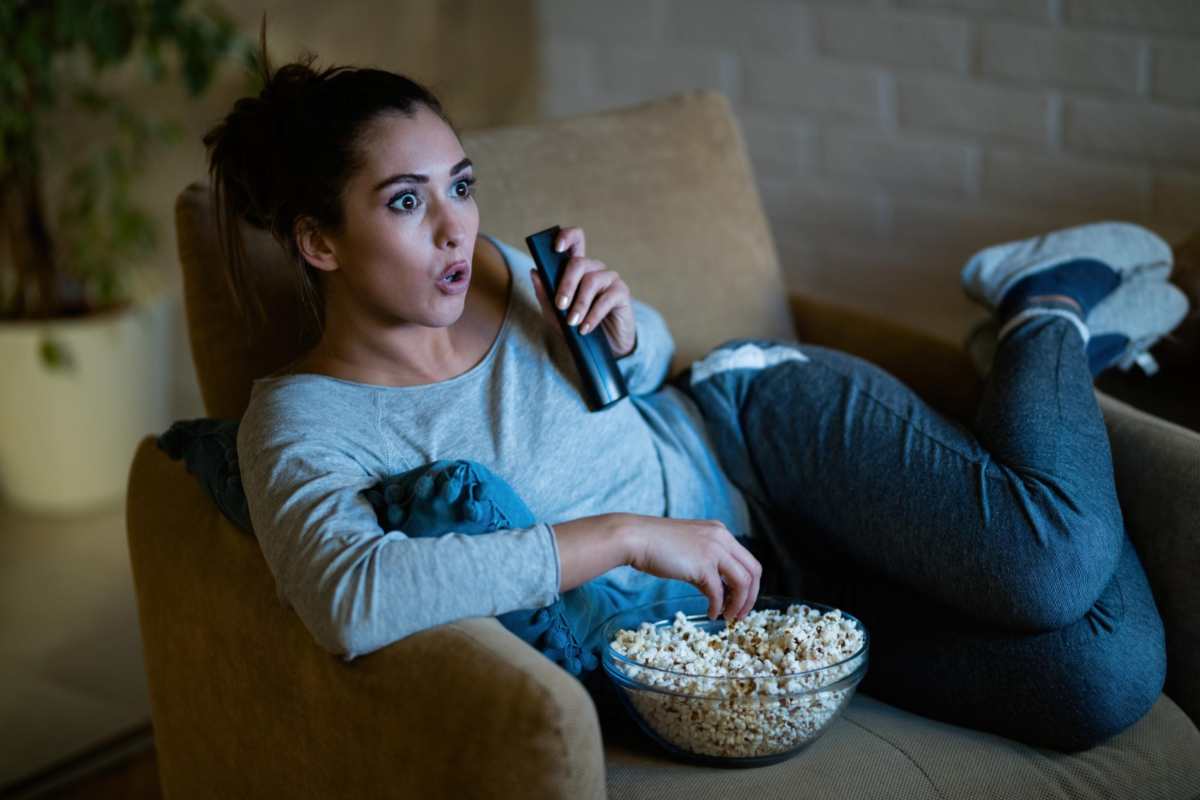 Giovane donna guarda la tv stupita